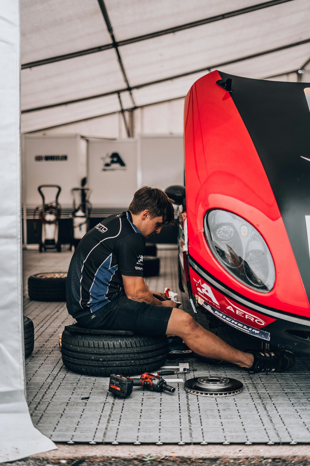 mechanic working on red ginetta racing car parked in garage during daytime