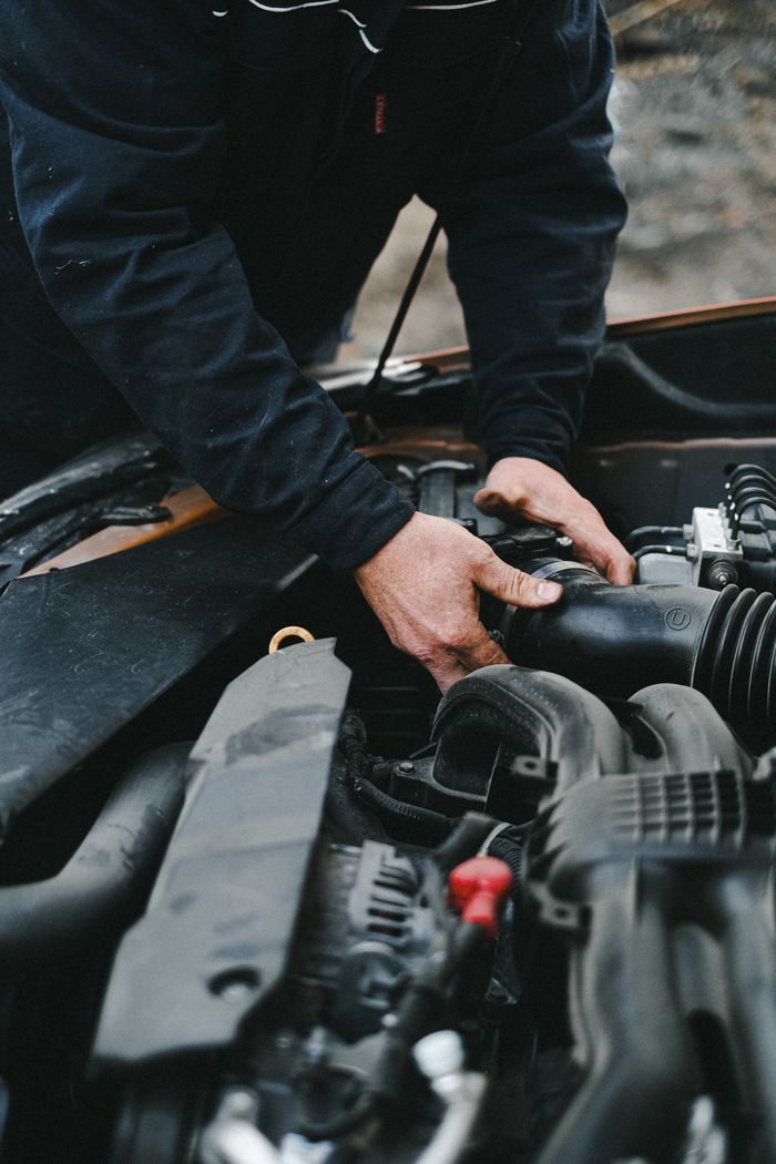 our-experience Close-up of a mechanics hands working on a car engine inside a workshop.