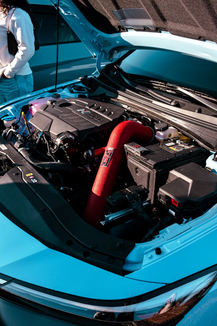 ours-journey Photo of an open car hood displaying a powerful engine with a striking red air filter.