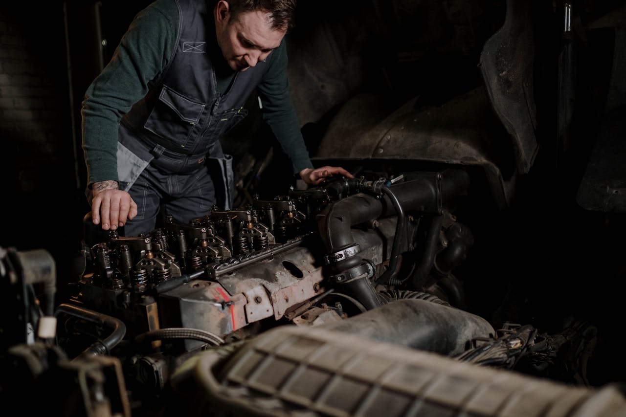 about-img Mechanic focused on vehicle engine repair in an indoor workshop.