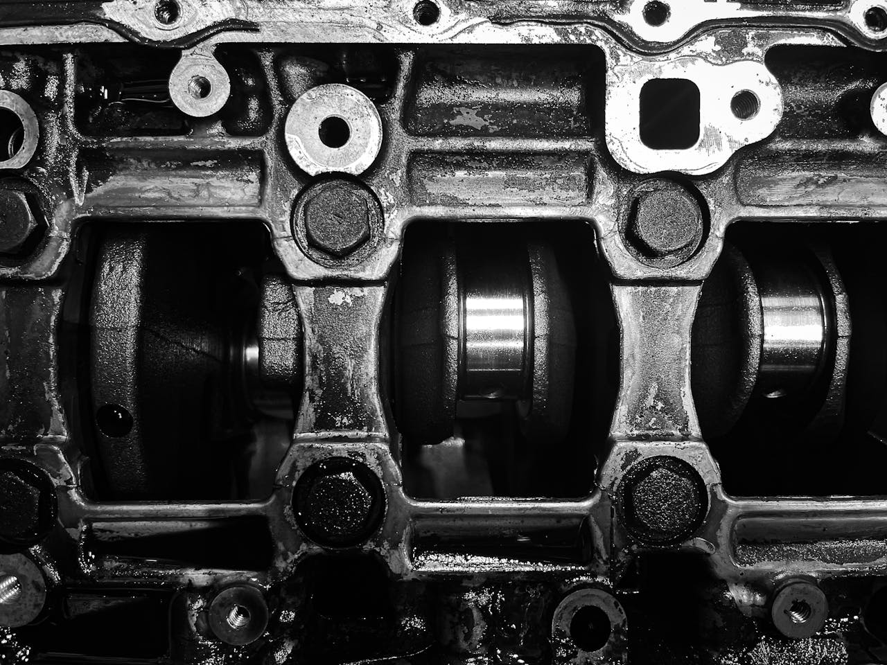 about-02 Detailed black and white close-up of a metal engine crankshaft mechanism.